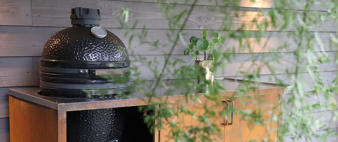 Stijlvolle buitenkeuken met RVS werkblad en ingebouwde barbecue in een zonnige tuin.