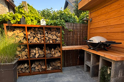 Grote cortenstalen houtopslag van 150 x 150 cm met negen vakken voor het overzichtelijk opslaan van haardhout in tuin of op terras.